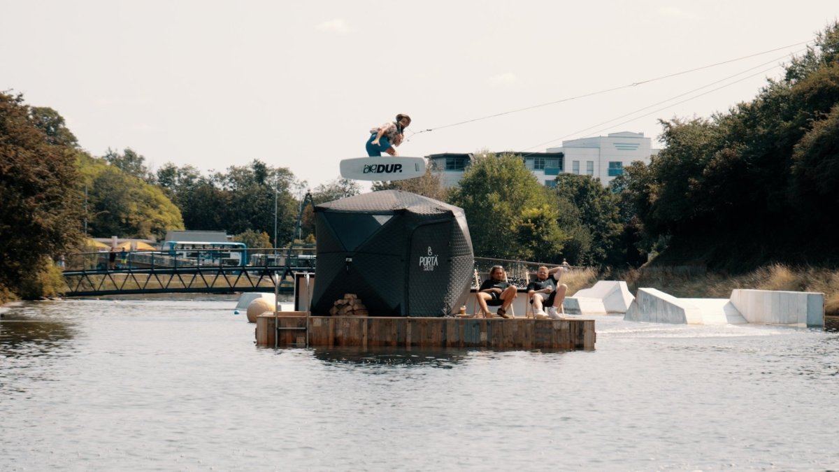 Wakeboarding over a wood fired PortaSauna; action day combining watersports with outdoor sauna.