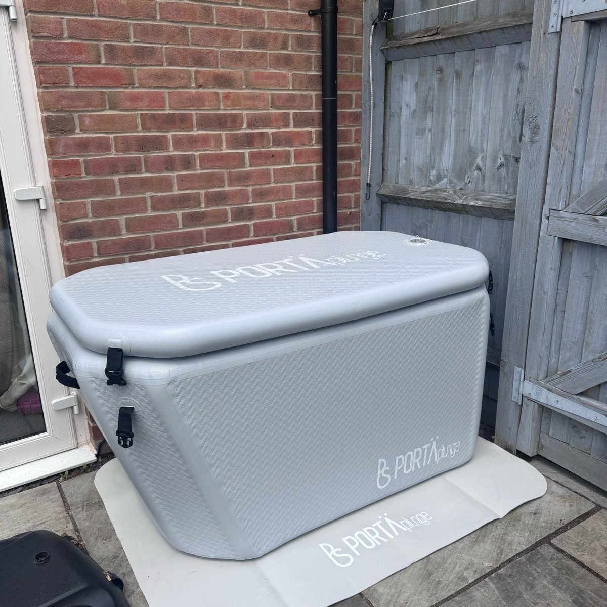 Gray cooler box with 'B-Porta' branding on a patio area.