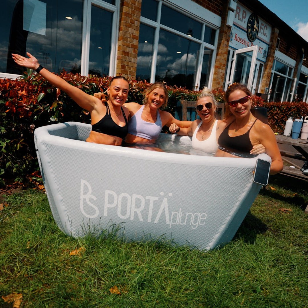 Group of people posing with a portable hot tub branded 'Portá' in an outdoor setting.